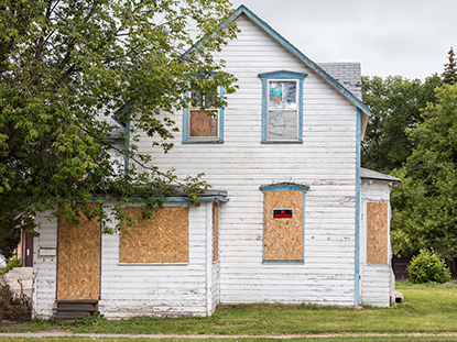 white house with boarded up windows and door