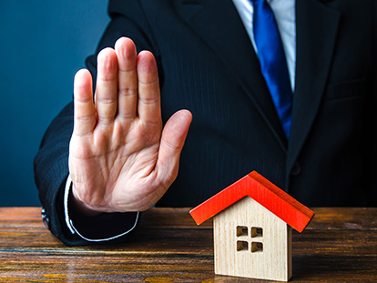 person holding up no hand with house in front