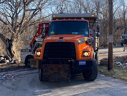 City trash truck picking up litter, trash, tires